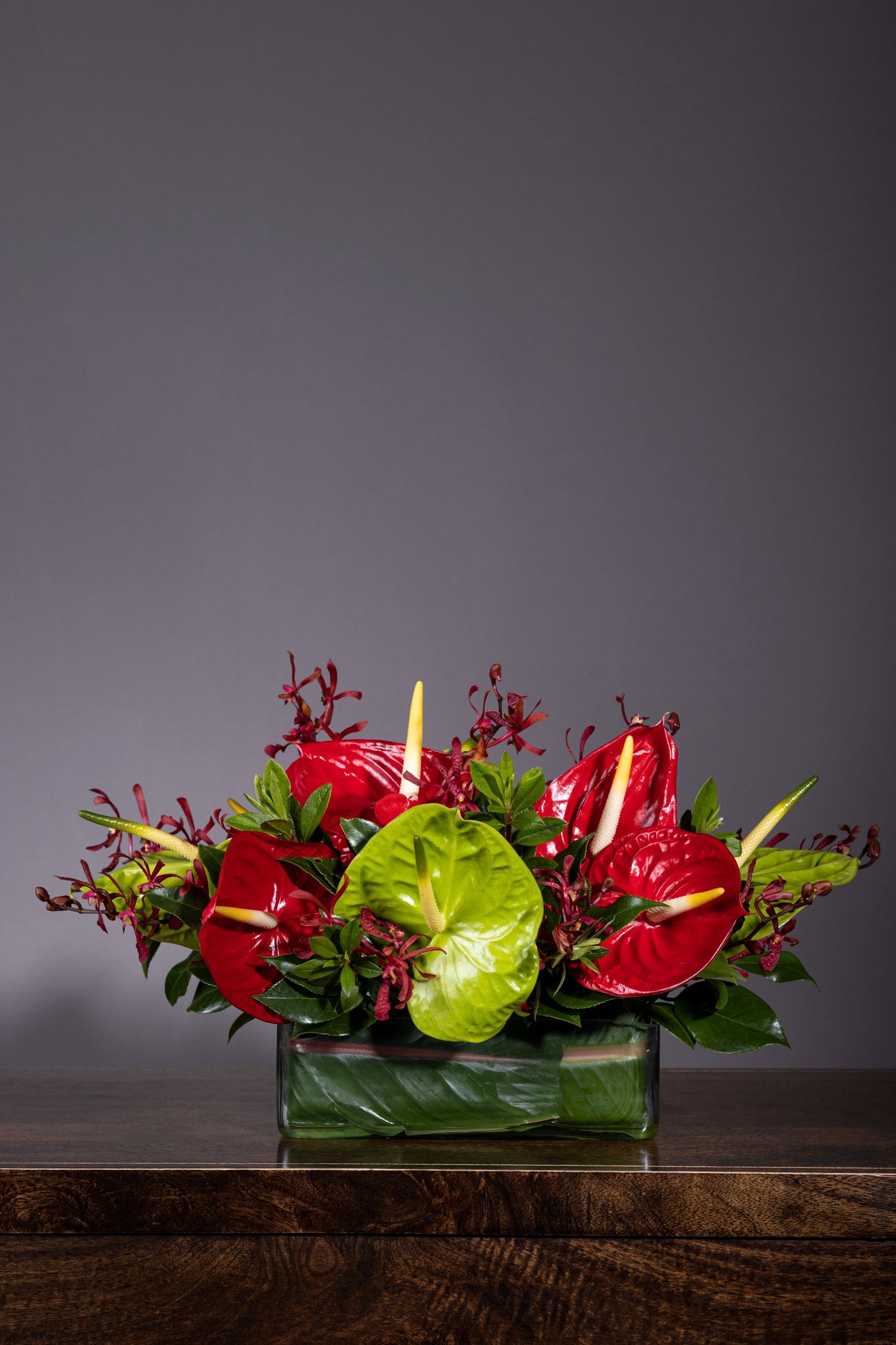 Hearts of Love - Beautiful centerpiece arrangement with Red and Green Anthurium flowers and Red Orchids in a long glass container | Flower delivery in Bengaluru | Buy flower bouquets online Bengaluru | Same-day flower delivery Bengaluru | Online florist Bengaluru | Order flowers online Bengaluru | Luxury flower bouquet in Bengaluru