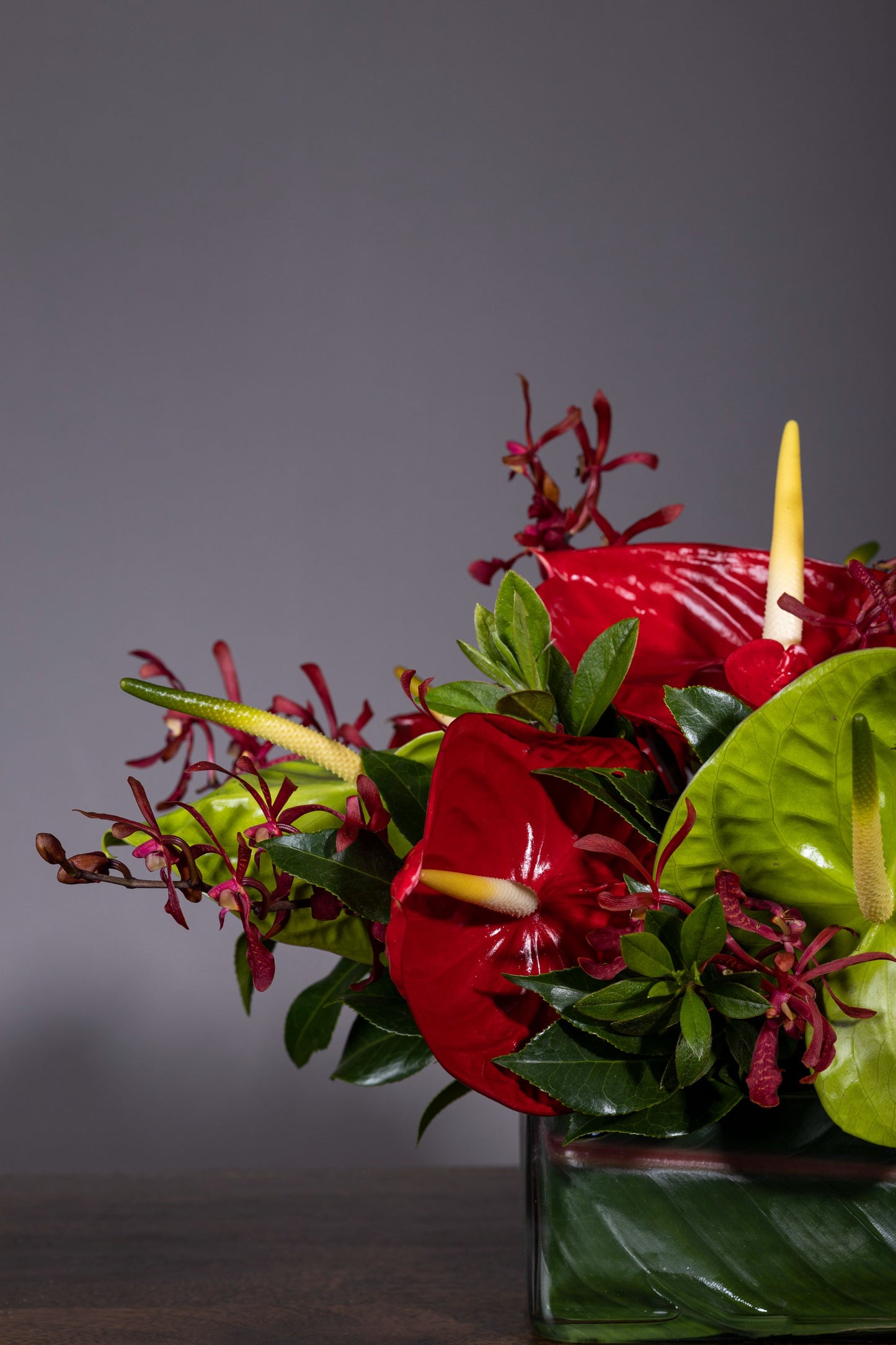 Hearts of Love - Beautiful centerpiece arrangement with Red and Green Anthurium flowers and Red Orchids in a long glass container | Flower delivery in Bengaluru | Buy flower bouquets online Bengaluru | Same-day flower delivery Bengaluru | Online florist Bengaluru | Order flowers online Bengaluru | Luxury flower bouquet in Bengaluru
