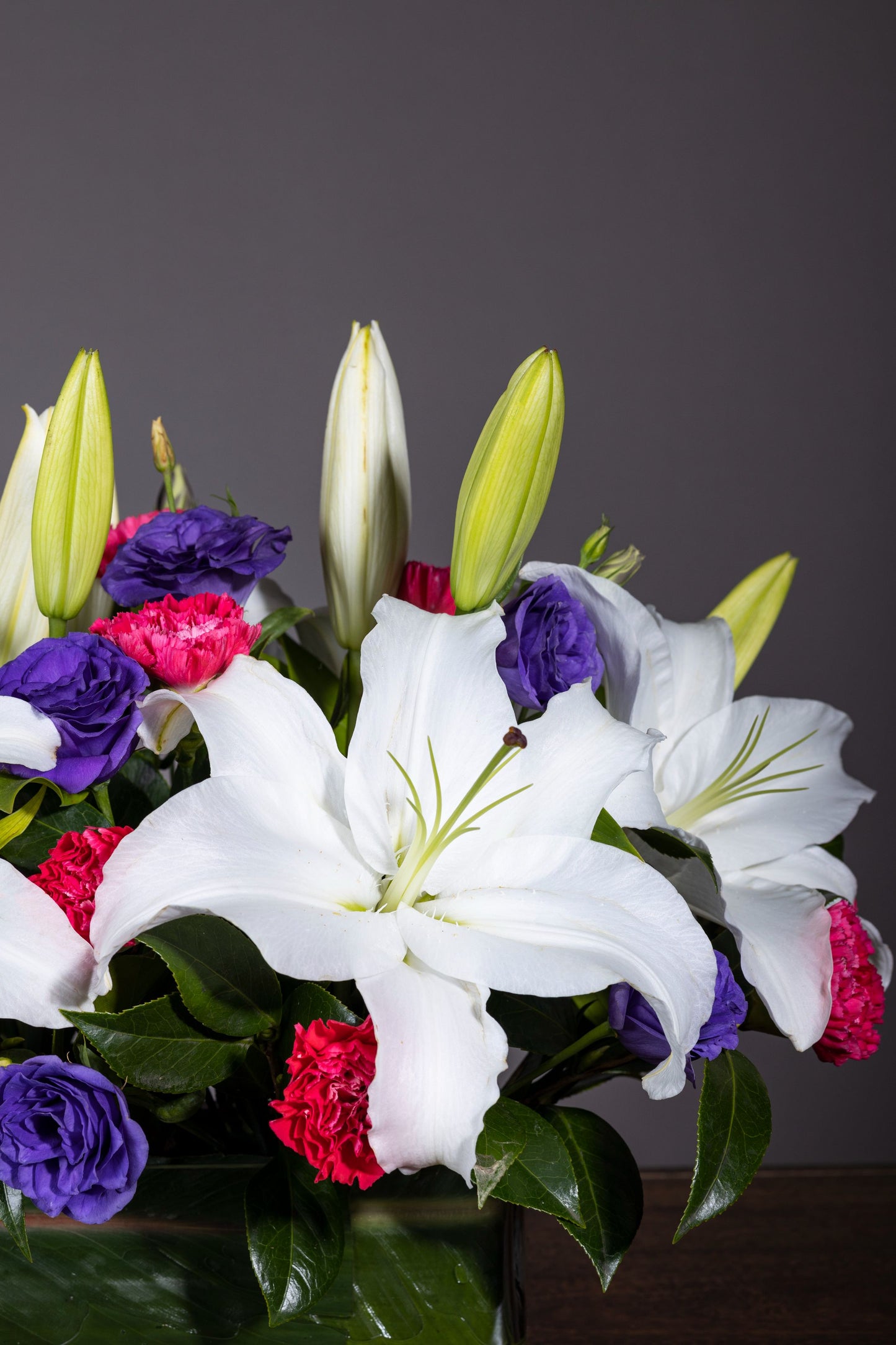 Casa Blanca - Elegant centerpiece with pure White Lilies and colorful Spray Carnations in a lush foliage bed | Flower delivery in Bengaluru | Buy flower bouquets online Bengaluru | Same-day flower delivery Bengaluru | Online florist Bengaluru | Order flowers online Bengaluru | Luxury flower bouquet in Bengaluru
