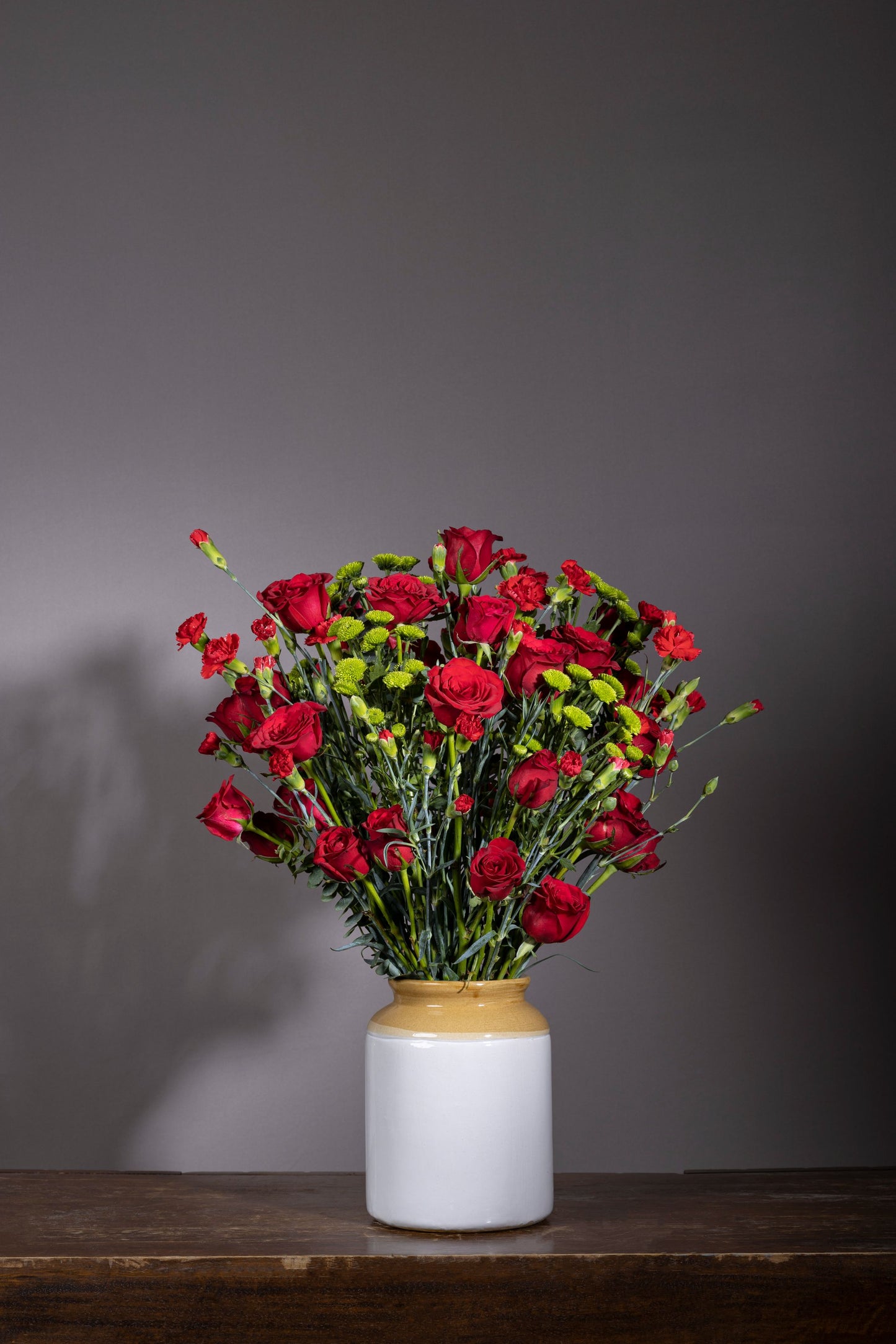 RED HAZE – Stunning red roses, red carnation sprays, and green chrysanthemum stems in a pickle jar – Flower delivery in Bengaluru, Buy flower bouquets online Bengaluru, Same-day flower delivery Bengaluru, Online florist Bengaluru, Order flowers online Bengaluru, Luxury flower bouquet in Bengaluru