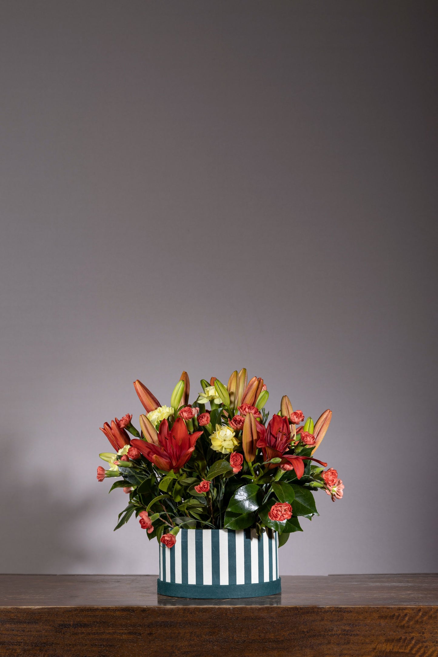 Big Hugs - A custom signature keepsake box with maroon lilies and yellow carnations, accented by exotic foliage. Perfect for birthdays, anniversaries, thank you gifts, congratulations, and new baby celebrations. Flower delivery in Bengaluru | Buy flower bouquets online Bengaluru | Same-day flower delivery Bengaluru | Online florist Bengaluru | Order flowers online Bengaluru | Luxury flower bouquet in Bengaluru