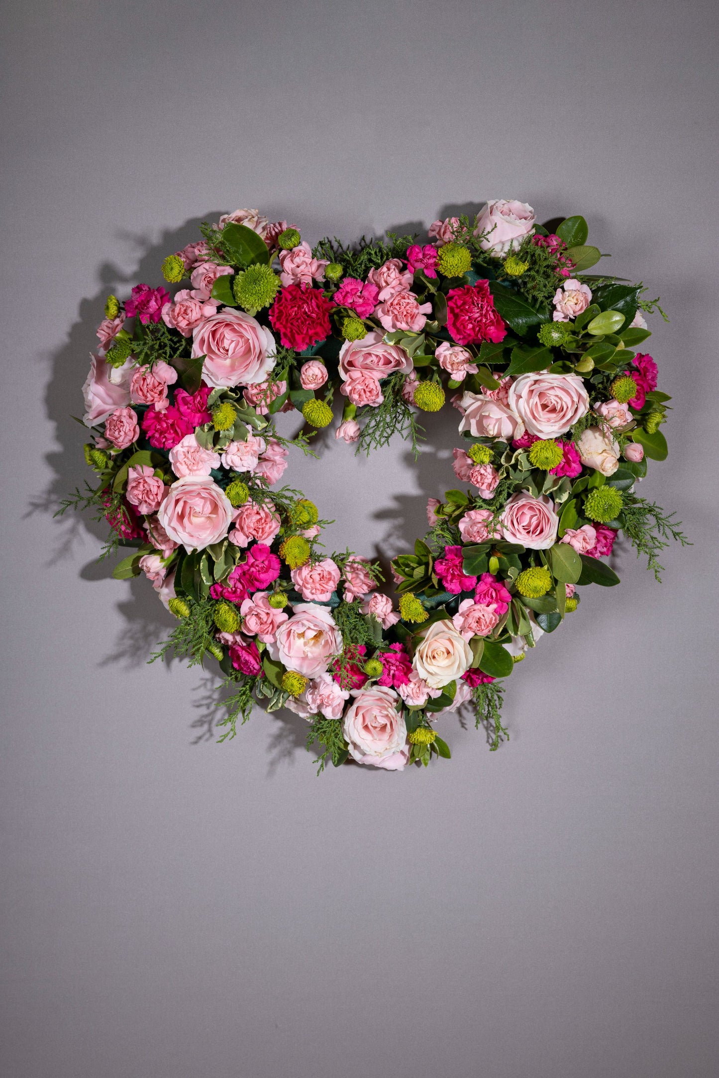 Heartfelt – A stunning heart-shaped wreath adorned with delicate pastel blossoms, set against a lush green foliage base. A perfect gift for birthdays, anniversaries, thank you gestures, congratulations, and welcoming a new baby