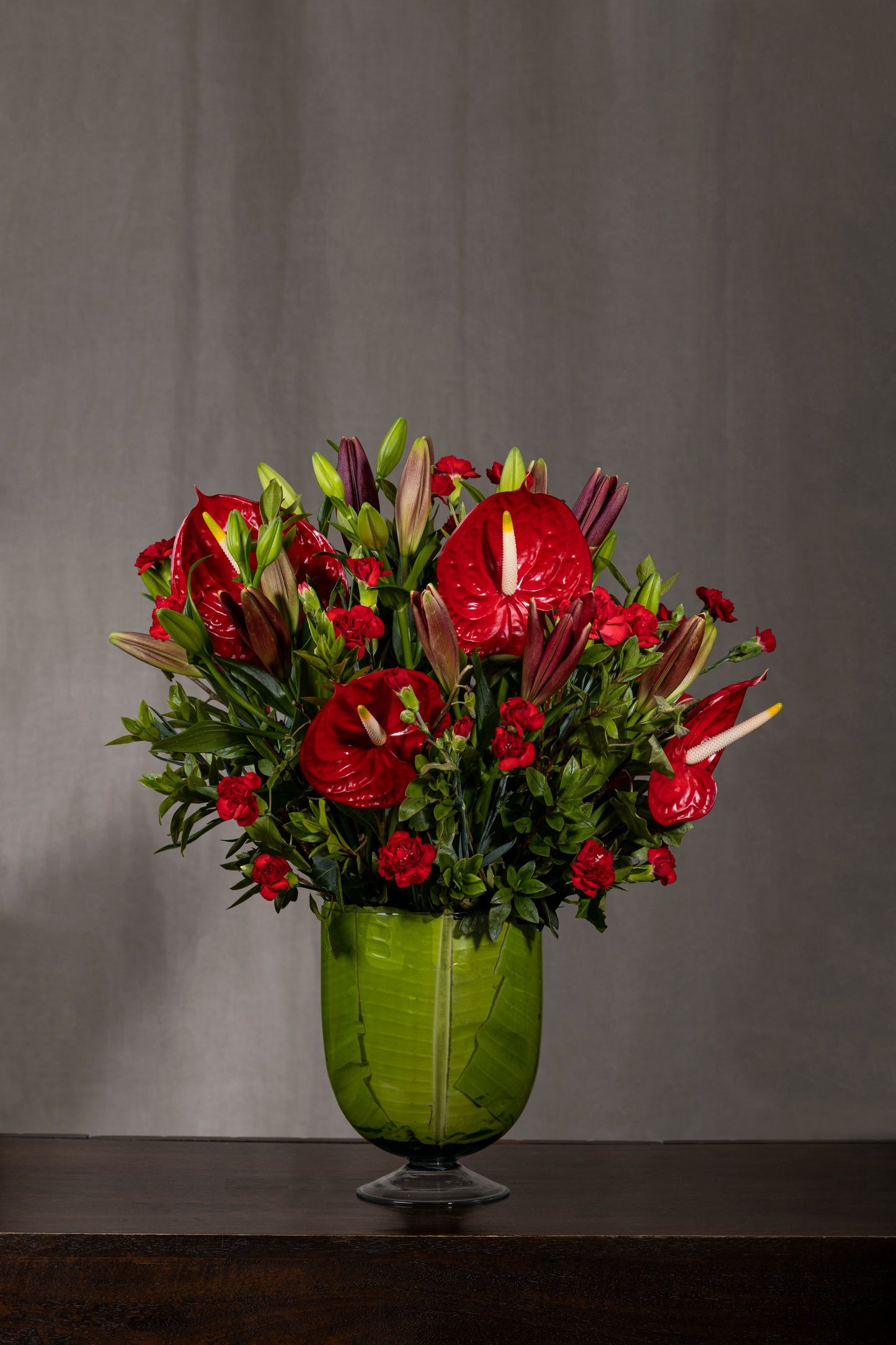 "Red in Rhapsody - Elegant glass bell jar with Red Anthuriums, Red Lilies, and Red Spray Carnations in a stunning red arrangement | Flower delivery in Bengaluru | Buy flower bouquets online Bengaluru | Same-day flower delivery Bengaluru | Online florist Bengaluru | Order flowers online Bengaluru | Luxury flower bouquet in Bengaluru