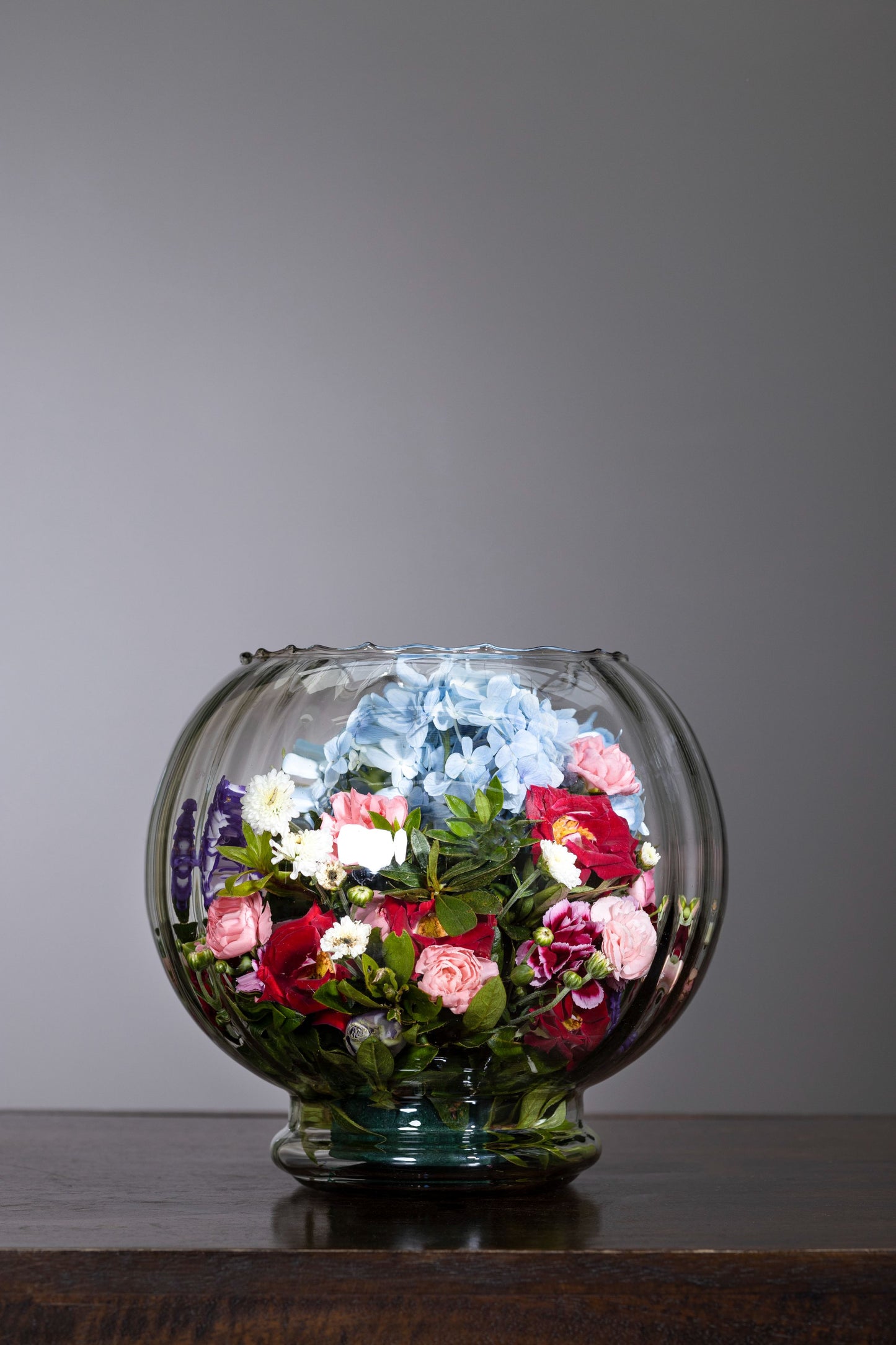 GRATEFUL - A delightful fish bowl arrangement featuring vibrant Red and Peach Spray Carnation blossoms, beautifully topped with a Blue Hydrangea garnish. Perfect for Birthdays, Anniversaries, Thank You, Congratulations, and New Baby. Flower delivery in Bengaluru, Buy flower bouquets online in Bengaluru, Same-day flower delivery Bengaluru, Online florist Bengaluru, Order flowers online Bengaluru, Luxury flower bouquet in Bengaluru