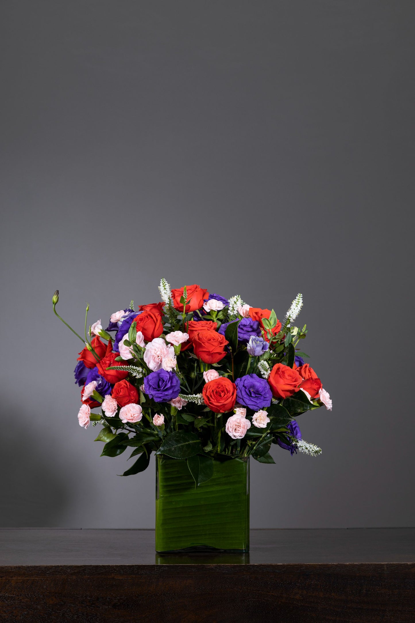 SPRING MELODY - A beautifully arranged leaf-lined cylindrical glass vase featuring pink Roses or Carnations, Purple Eustomas, and Spray Carnation stalks, creating a harmonious floral melody. Perfect for Birthdays, Anniversaries, Thank You, Congratulations, and New Baby. Flower delivery in Bengaluru, Buy flower bouquets online in Bengaluru, Same-day flower delivery Bengaluru, Online florist Bengaluru, Order flowers online Bengaluru, Luxury flower bouquet in Bengaluru.