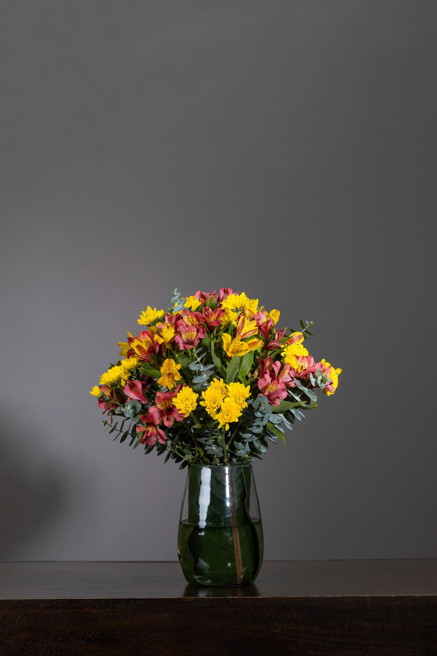 AUTUMN EMBRACE - A stylish leaf-lined glass vase beautifully arranged with vibrant Yellow Chrysanthemums and Alstroemeria, capturing the warm essence of autumn. Perfect for Birthdays, Anniversaries, Thank You, Congratulations, and New Baby. Flower delivery in Bengaluru, Buy flower bouquets online in Bengaluru, Same-day flower delivery Bengaluru, Online florist Bengaluru, Order flowers online Bengaluru, Luxury flower bouquet in Bengaluru