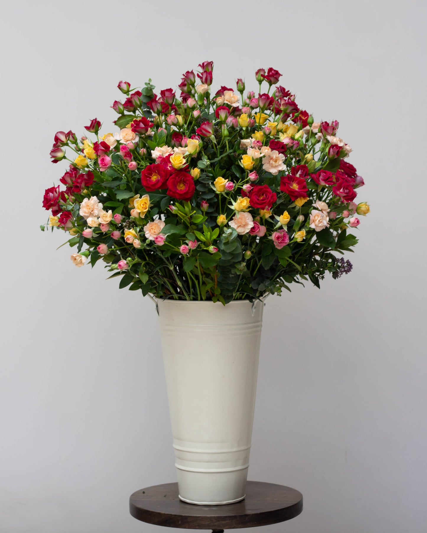 Premium flower delivery featuring a big flower bouquet of red, pink, and yellow spray roses with peach spray carnations in a tall custom tin, symbolizing eternal love. Perfect for same-day florist delivery, online flower delivery in Bangalore, and bouquet delivery near you. Ideal for anniversaries, birthdays, and special occasions. Order now for luxury flower arrangements, high-end bouquets, and home delivery flowers.