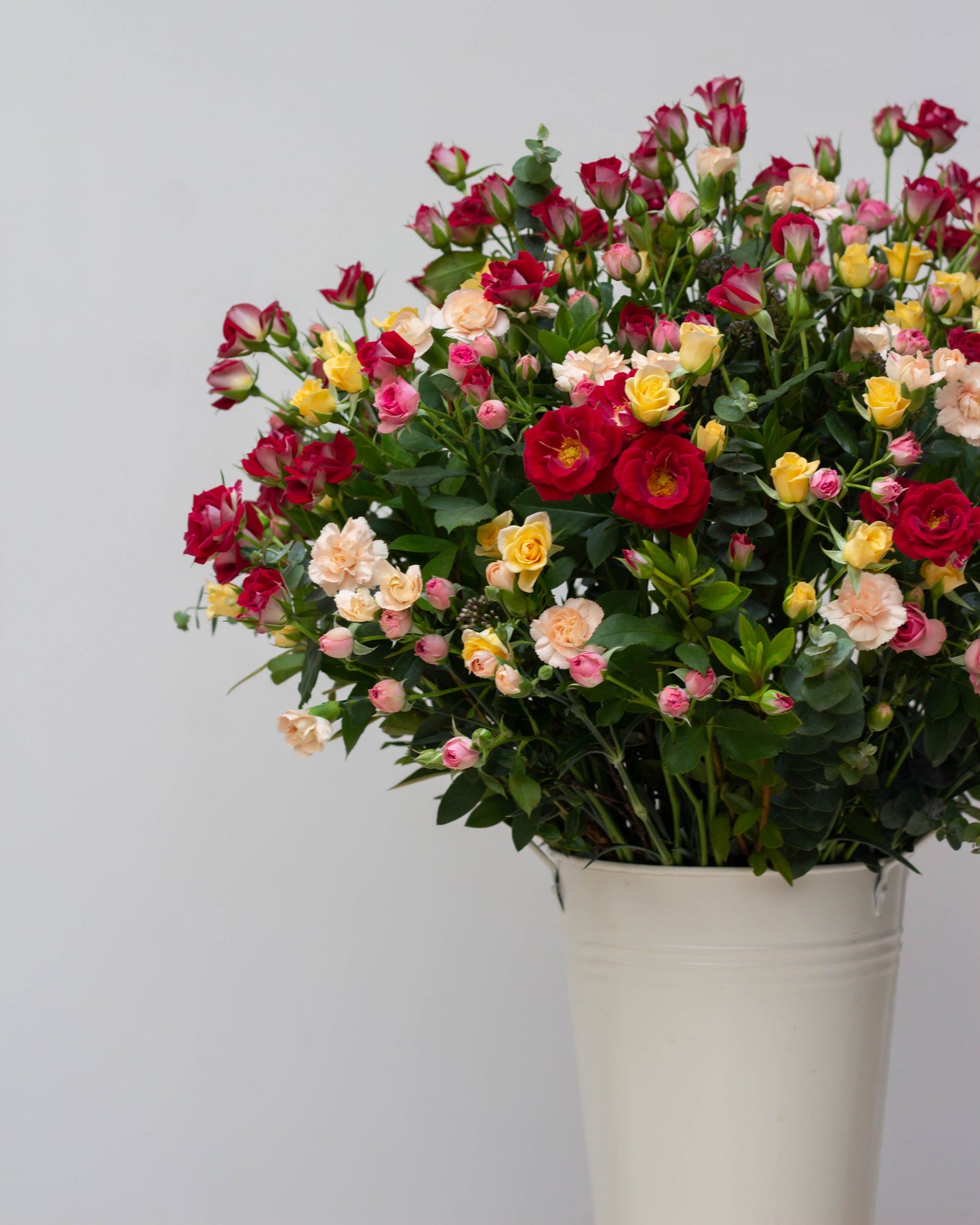 Premium flower delivery featuring a big flower bouquet of red, pink, and yellow spray roses with peach spray carnations in a tall custom tin, symbolizing eternal love. Perfect for same-day florist delivery, online flower delivery in Bangalore, and bouquet delivery near you. Ideal for anniversaries, birthdays, and special occasions. Order now for luxury flower arrangements, high-end bouquets, and home delivery flowers.