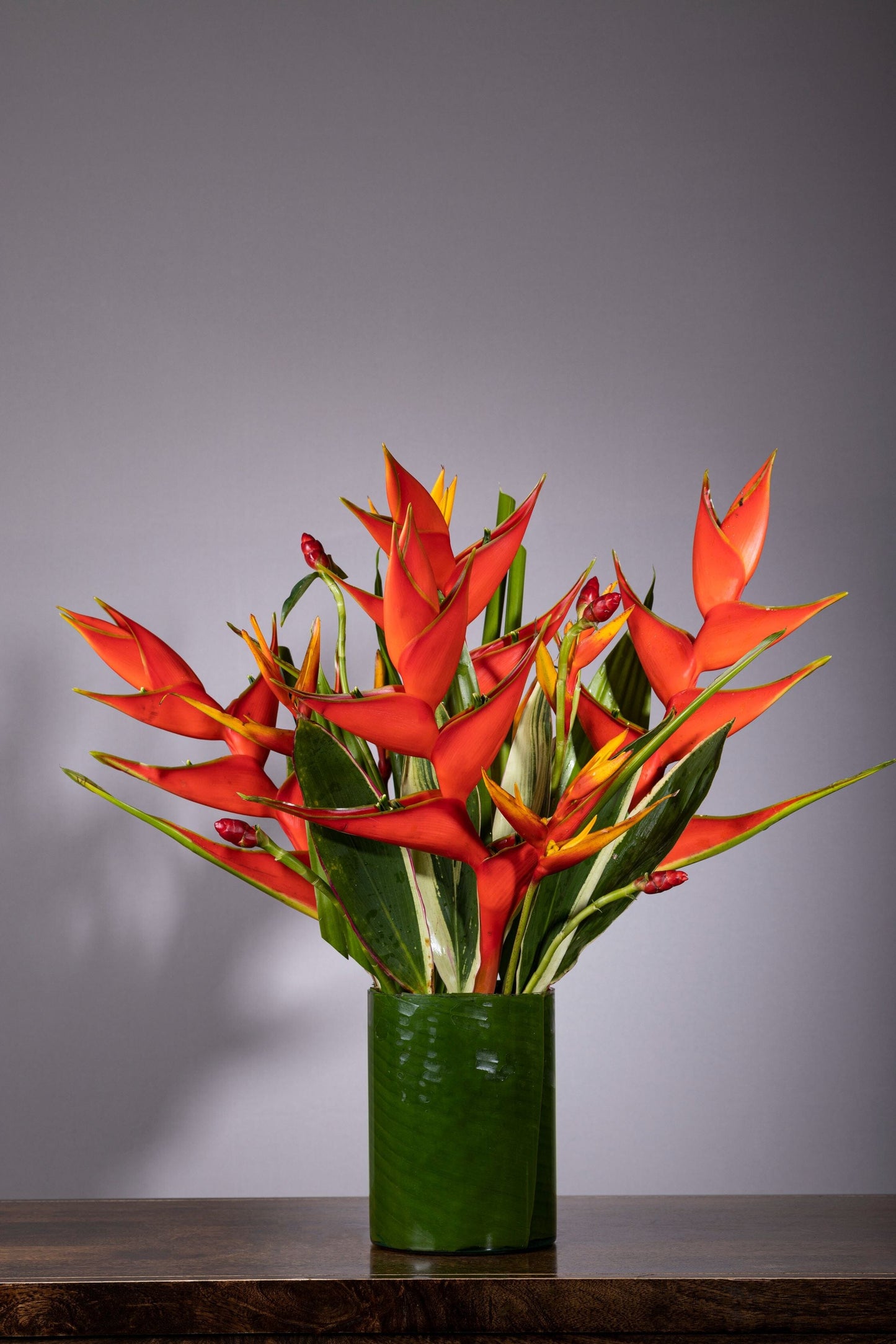 Majestic Flower Bouquet | Luxury flower bouquet in Bengaluru, ohanafineflowers: Same-day delivery featuring a stunning arrangement of tropical Heliconias in a glass vase, elegantly set against a lush foliage backdrop, perfect for Birthdays, Anniversaries, Thank You, and Congratulations gifts
