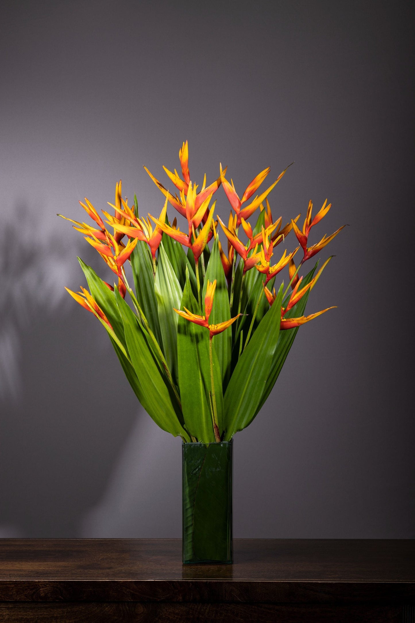 Million Smiles – Million Smiles best bouquet flowers in Bengaluru featuring a profusion of Baby Heliconia stems in a leaf-lined glass vase, complemented by lush foliage, perfect for Birthdays, Anniversaries, Thank You, Congratulations, and Get Well Soon gifts