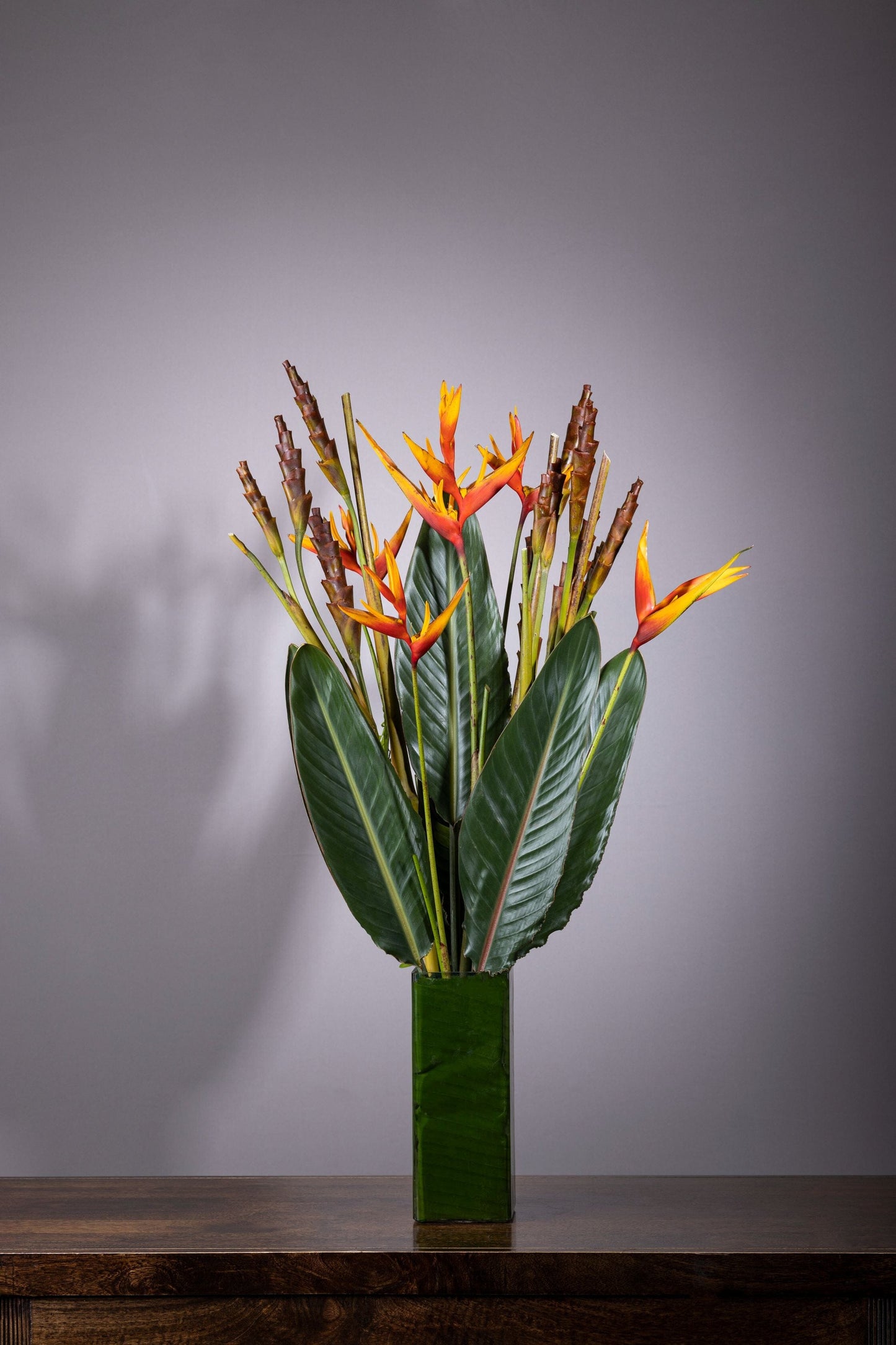 TROPICAL ESSENCE | Best bouquet flowers in Bengaluru, ohanafineflowers: Same-day delivery featuring a stunning blend of Calatheas and Baby Heliconia flowers in a medium-height square glass vase, accented with Bird of Paradise leaves, perfect for Birthdays, Anniversaries, Thank You, and Congratulations gifts
